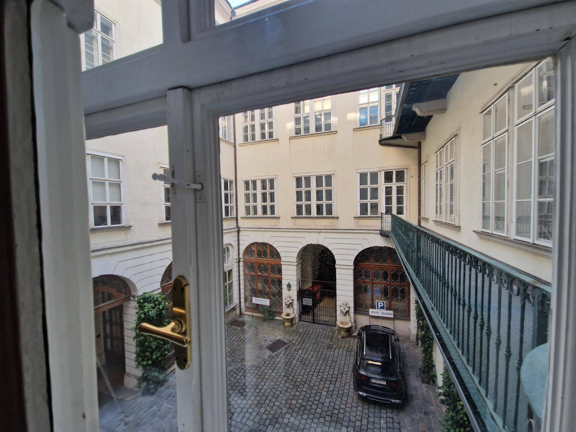 Blick aus einem Fenster auf einen historischen Innenhof mit Kopfsteinpflaster und Balkonen.