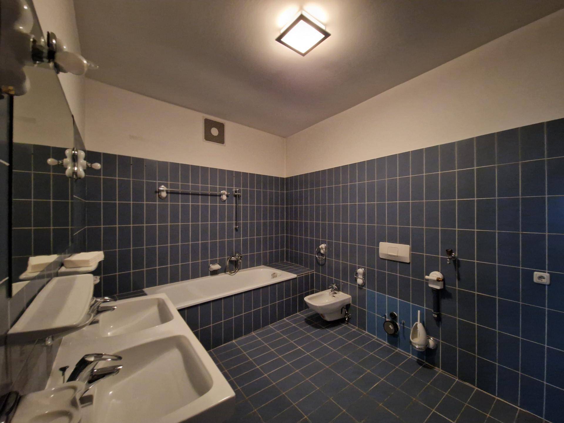 Badezimmer mit blauen Fliesen, Badewanne, Doppelwaschbecken und Bidet.