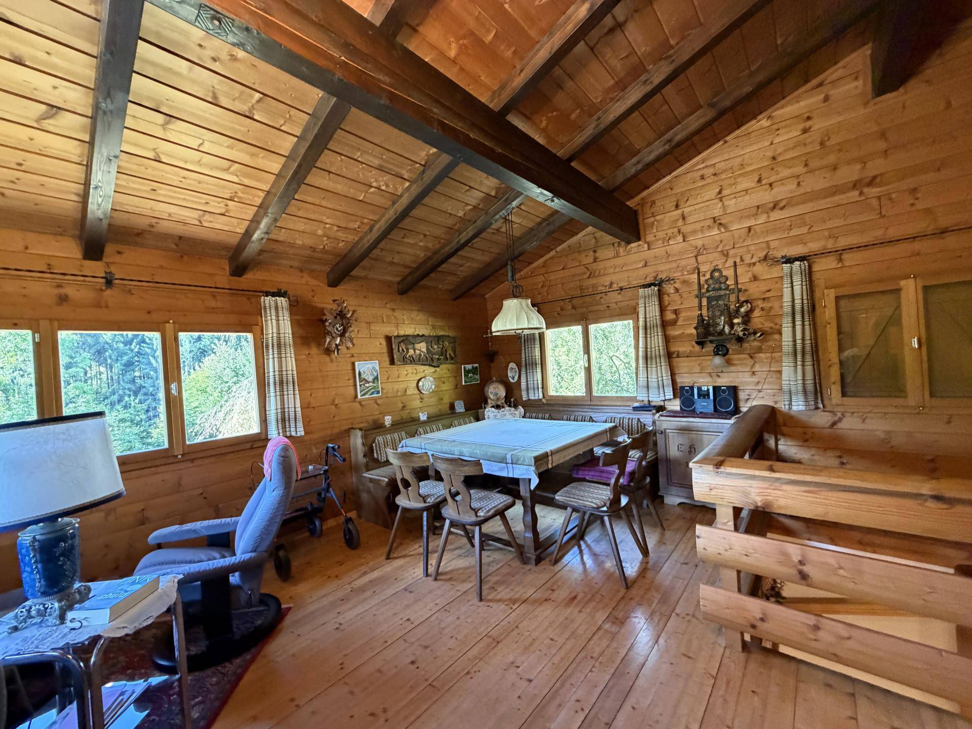 Gemütlicher Wohn-Essbereich im Chalet-Stil mit Holzwänden und Dachschrägen.