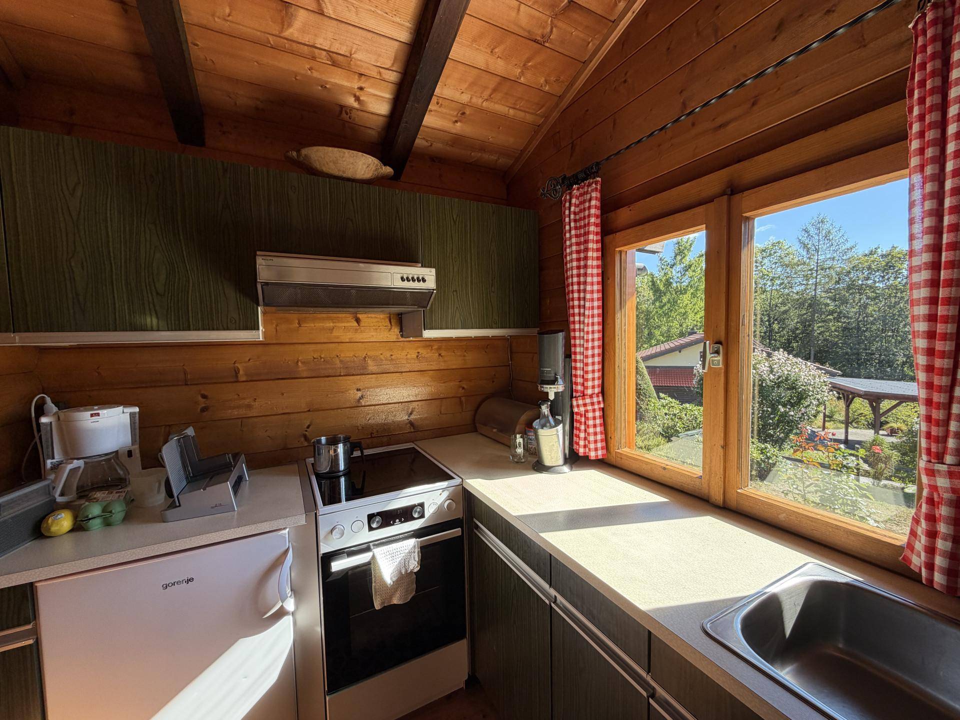 Kleine Küche im Landhausstil mit Holzvertäfelung, Fenster und Blick ins Grüne.