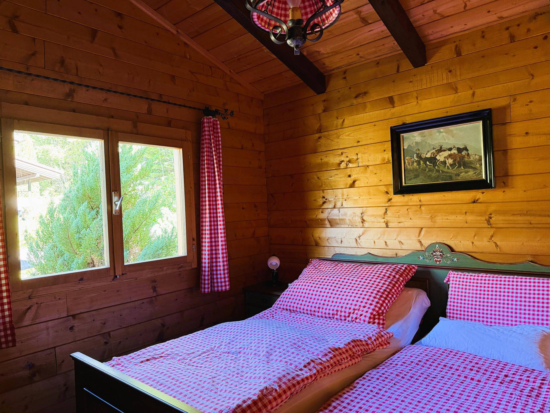 Schlafzimmer im Landhausstil mit Holzvertäfelung, Einzelbetten und karierter Bettwäsche.