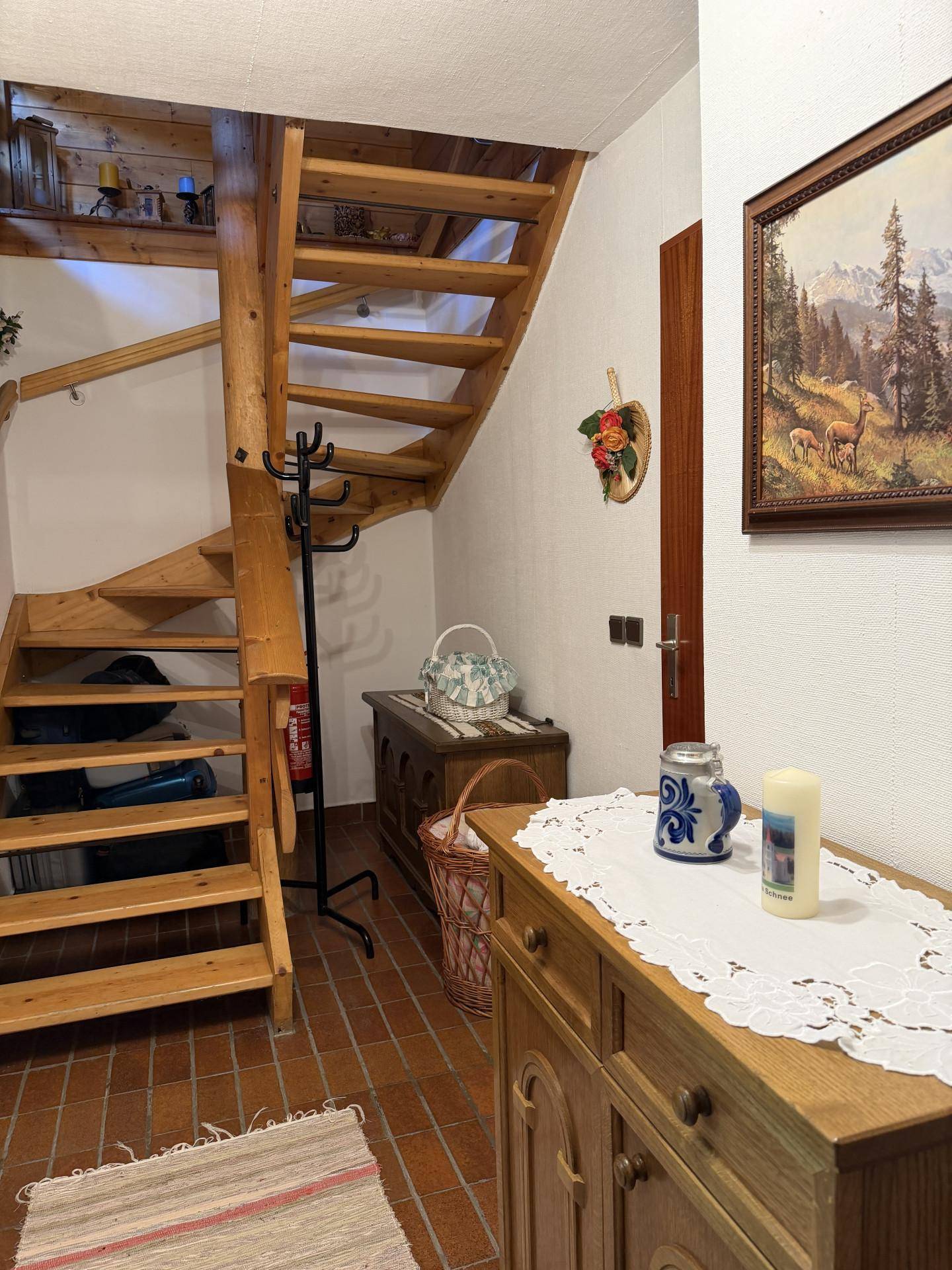 Heller Flur mit Holztreppe und traditioneller Dekoration, die zum Obergeschoss führt.