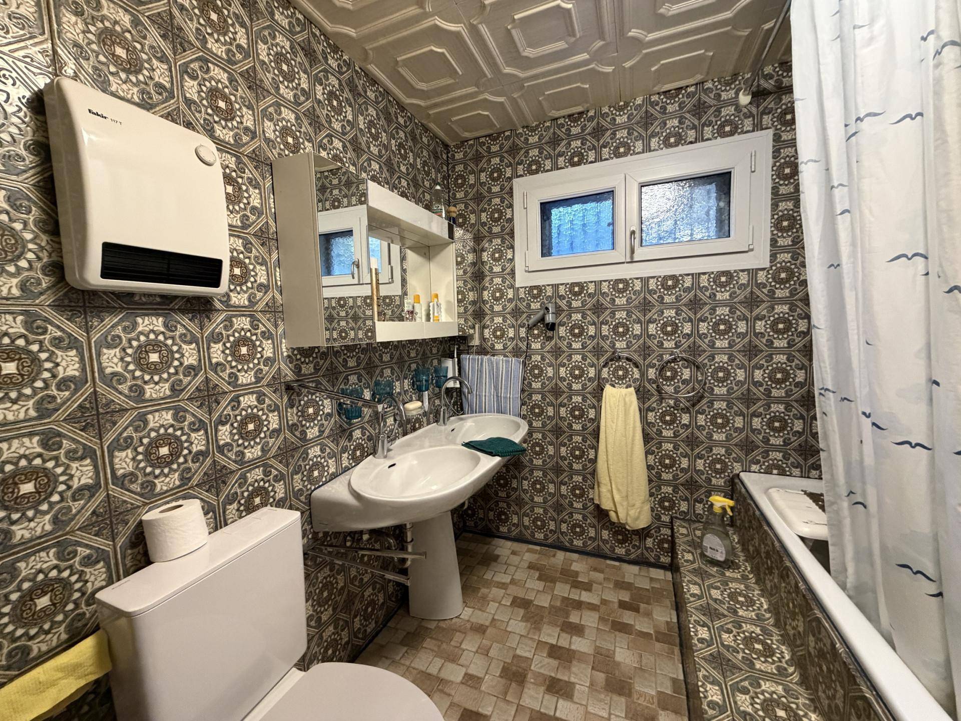 Badezimmer mit gemusterten Fliesen, Doppelwaschbecken und Badewanne.