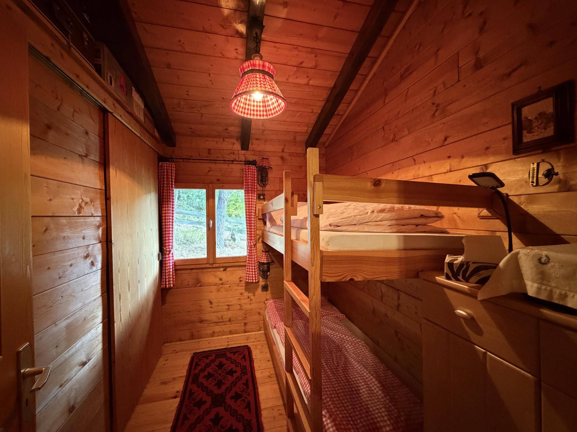 Kleines Schlafzimmer mit Etagenbetten und Holzvertäfelung, ideal für Kinder.