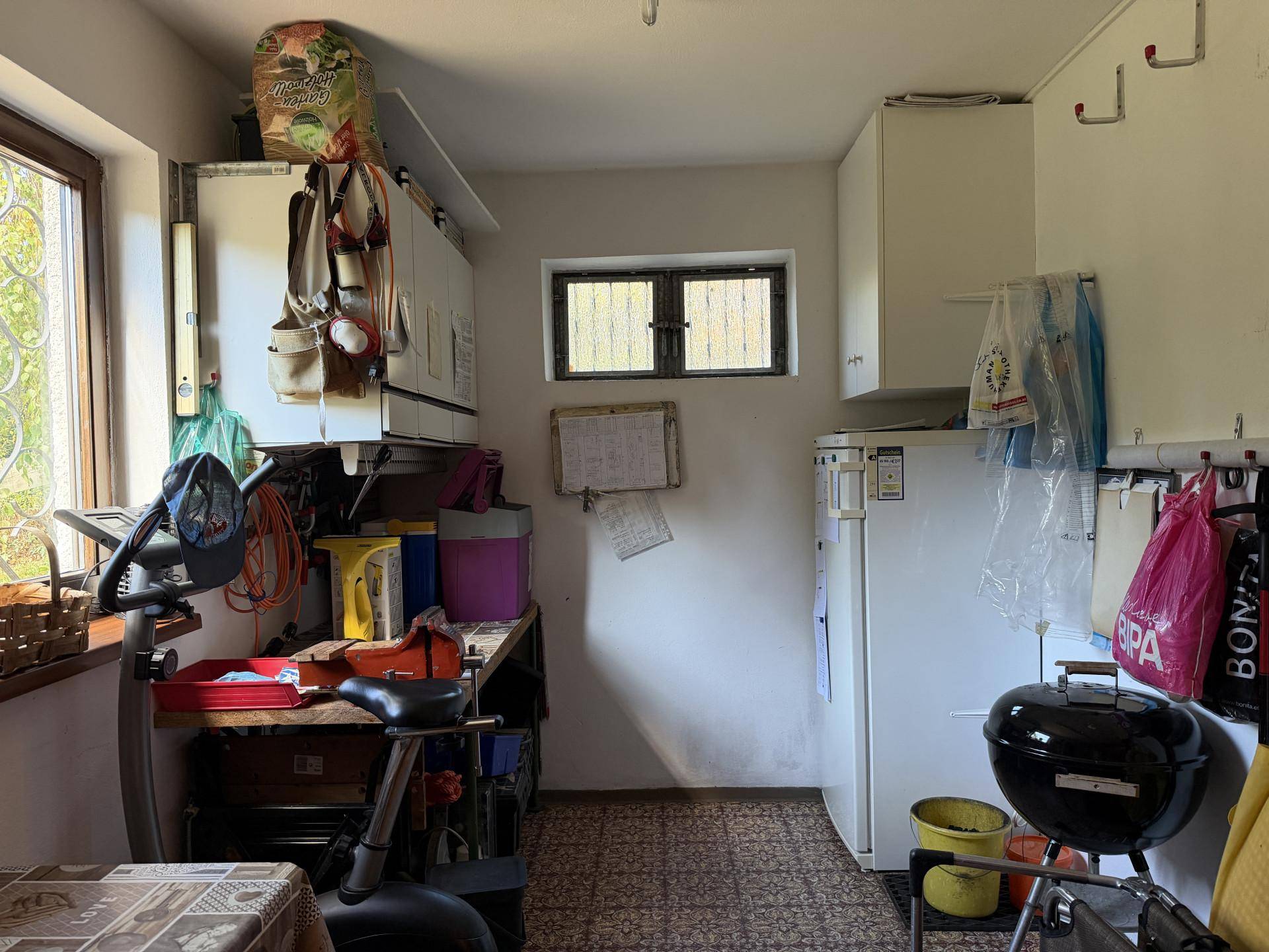 Praktischer Abstellraum mit Stauraum, Kühlschrank und Trainingsgerät.