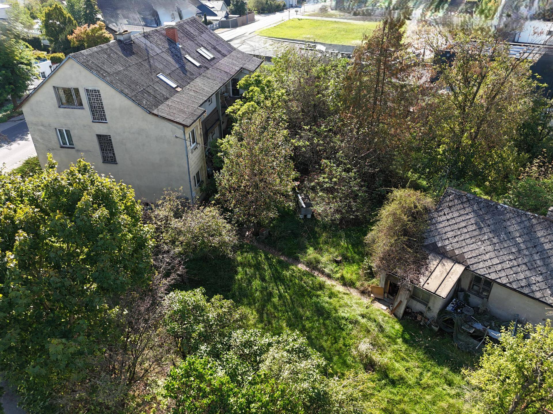 Übersicht des Anwesens von oben, mit einem älteren Wohnhaus und einem verwilderten Gartenbereich.