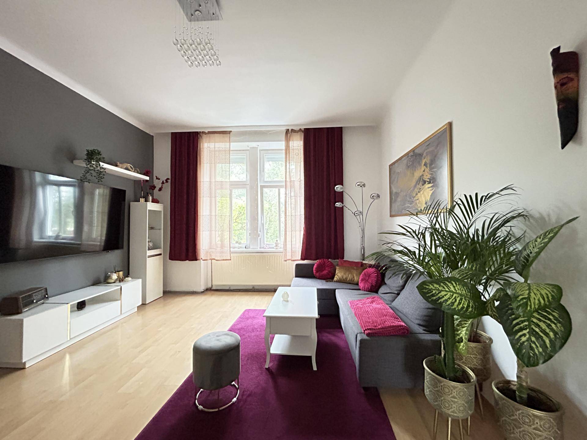 Gemütliches Wohnzimmer mit Fernseher, Sofa und dekorativen Elementen in warmen Farben.