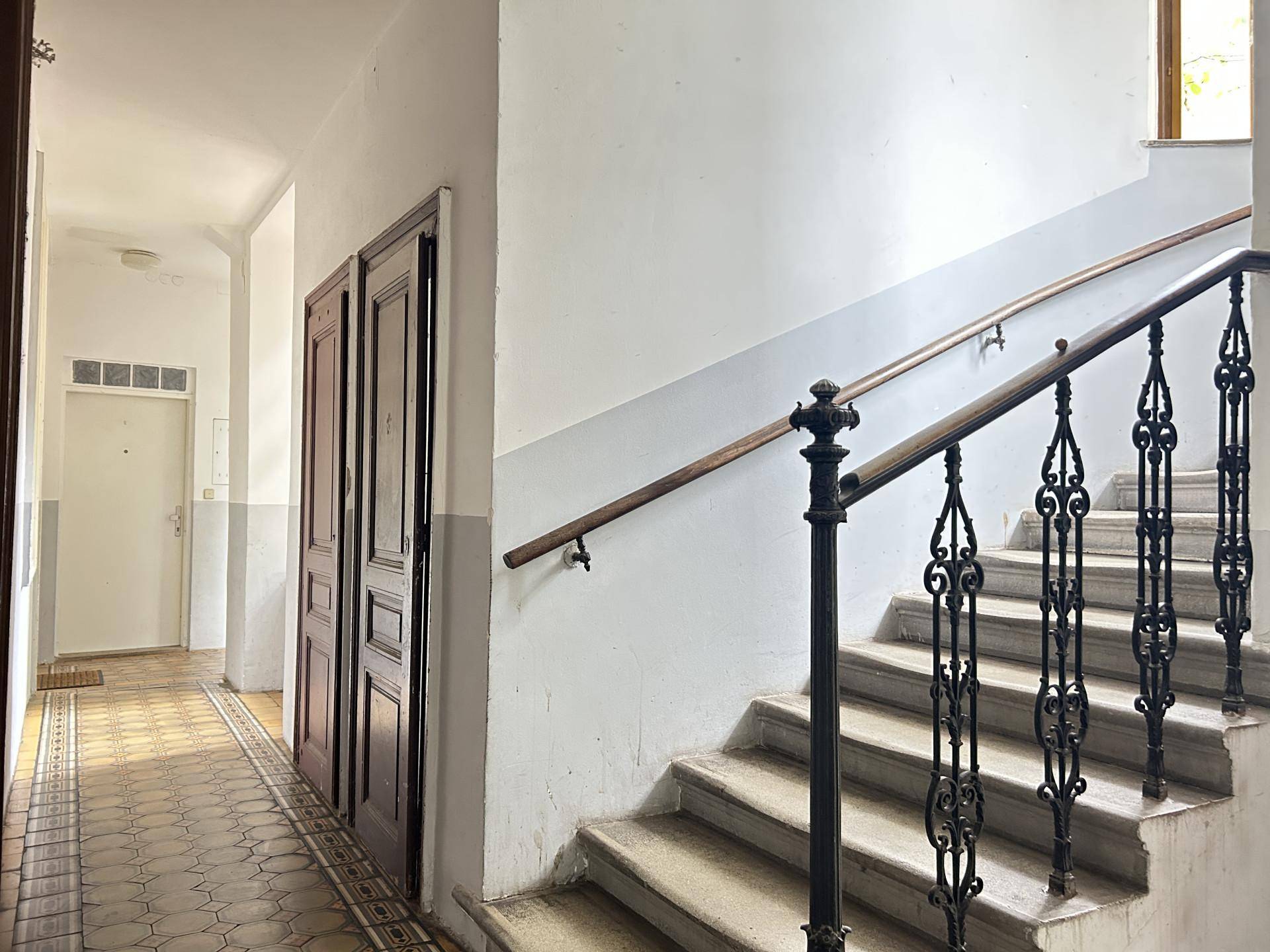 Treppenhaus mit historischem Geländer und gemustertem Bodenbelag.
