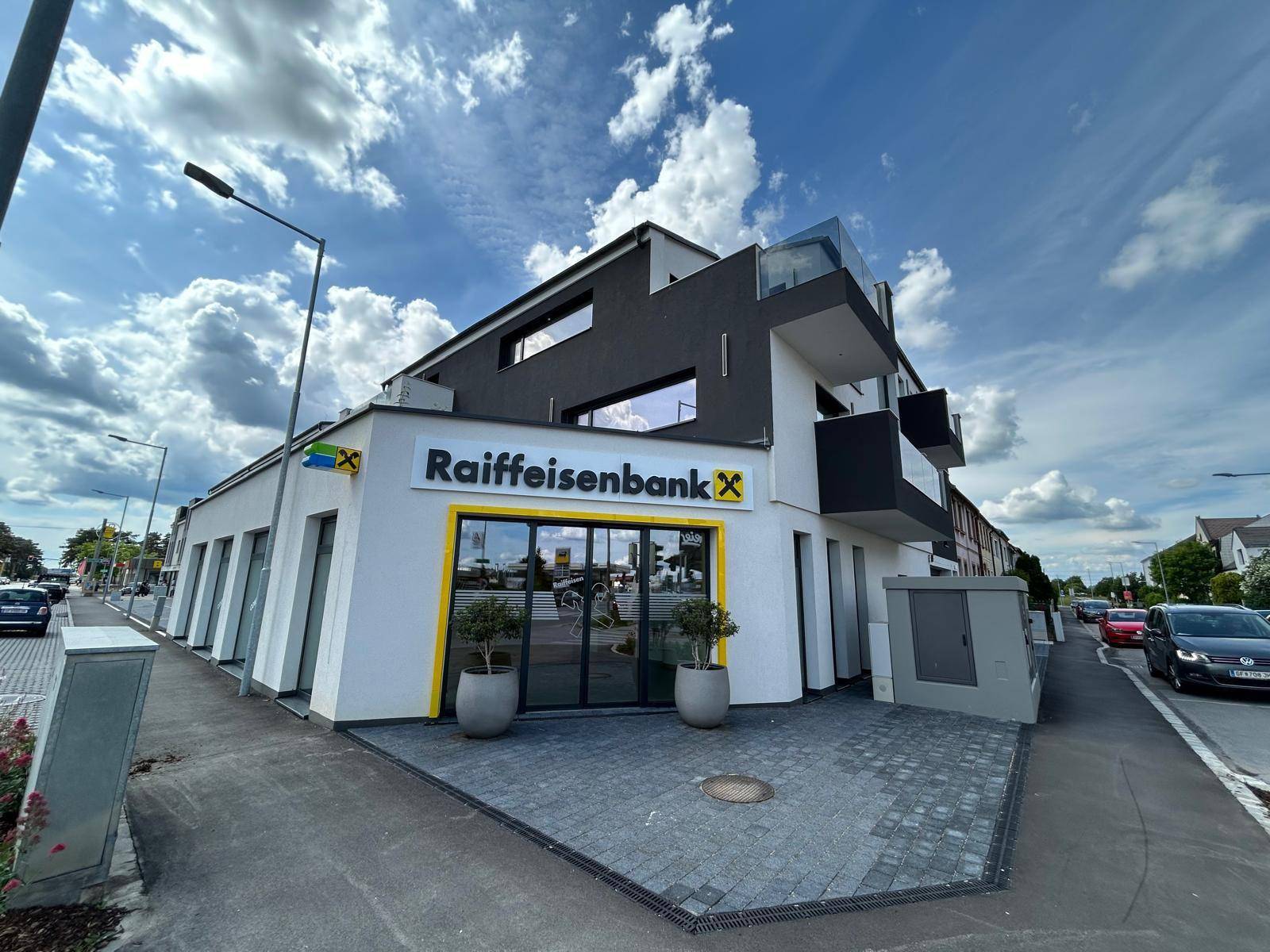 Eingangsbereich der modernen Raiffeisenbank-Filiale im Erdgeschoss des Neubaus mit klarem Design.