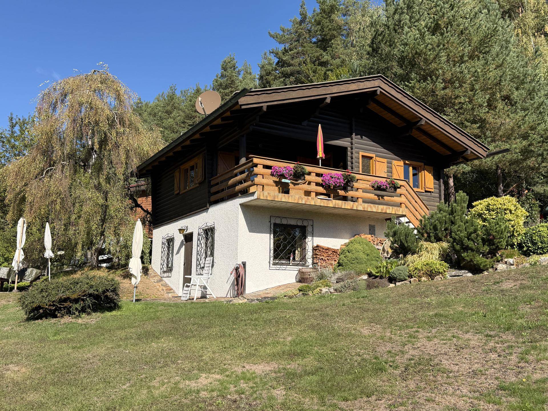 Traditionelles Holzchalet mit Balkon und gepflegtem Garten in ländlicher Umgebung.