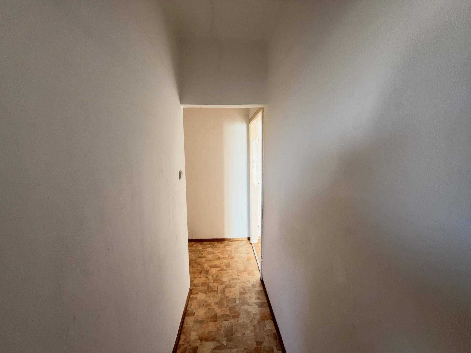 Schmaler Flur mit Laminatboden, der zu weiteren Räumen der Wohnung führt.