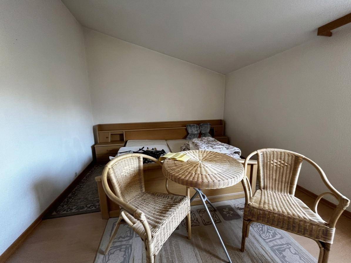 Schlafzimmer im Dachgeschoss mit Dachschräge, Teppichboden und Rattanmöbeln.