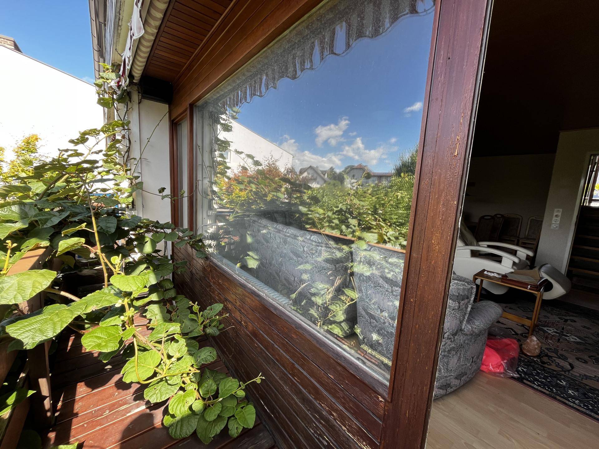 Blick aus einem verglasten Wintergarten in den Wohnbereich mit viel Tageslicht.