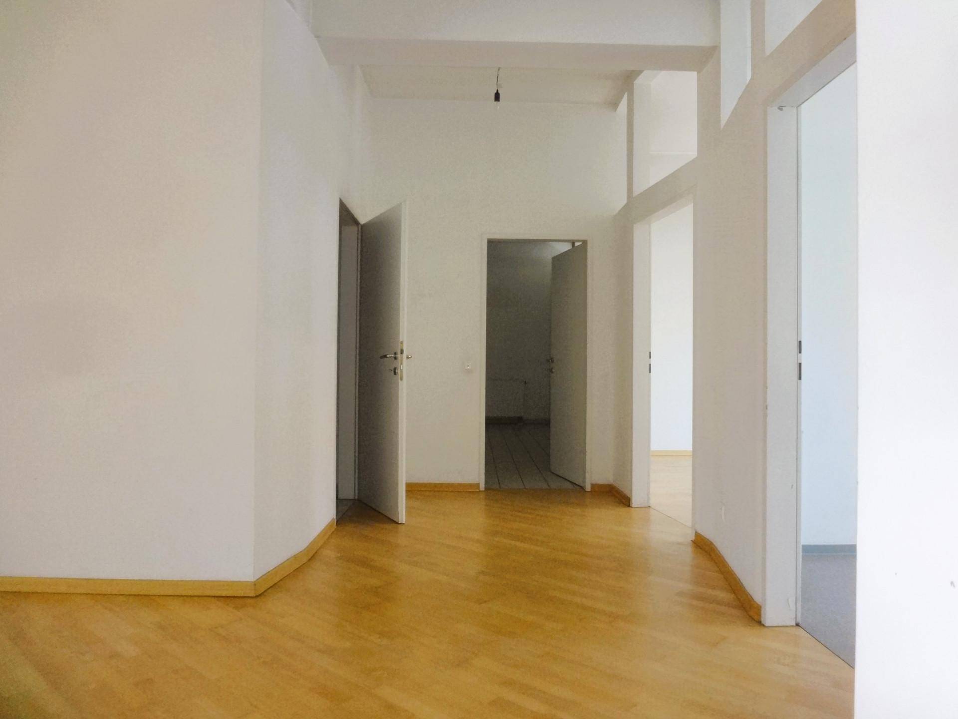 Heller, offener Innenraum mit Parkettboden und mehreren Türen, der vielseitige Nutzungsmöglichkeiten bietet.