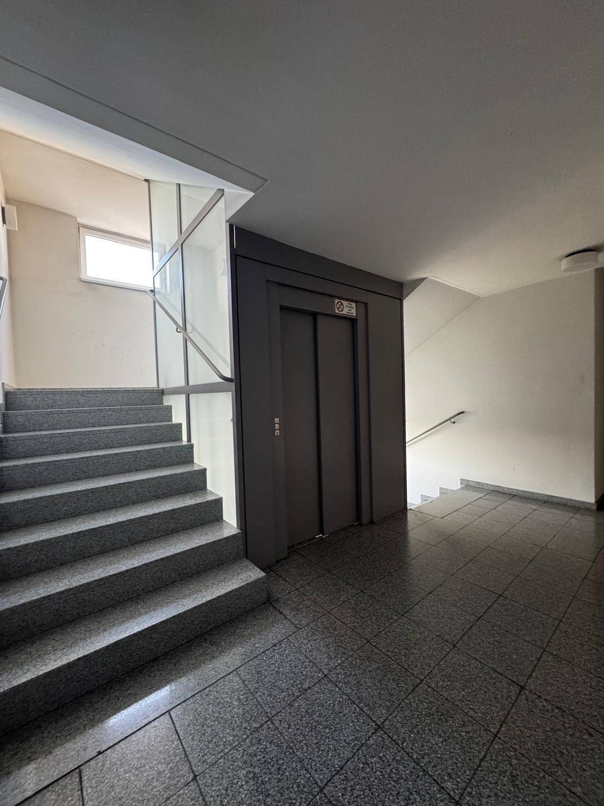 Treppenhaus mit Granitstufen und Aufzug in einem Mehrfamilienhaus, bietet bequemen Zugang zu allen Etagen.