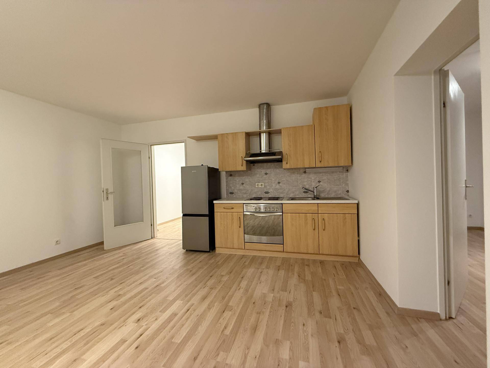 Funktionale Küchenzeile mit hellem Laminatboden und Blick in angrenzende Zimmer, ideal für offenes Wohnen.