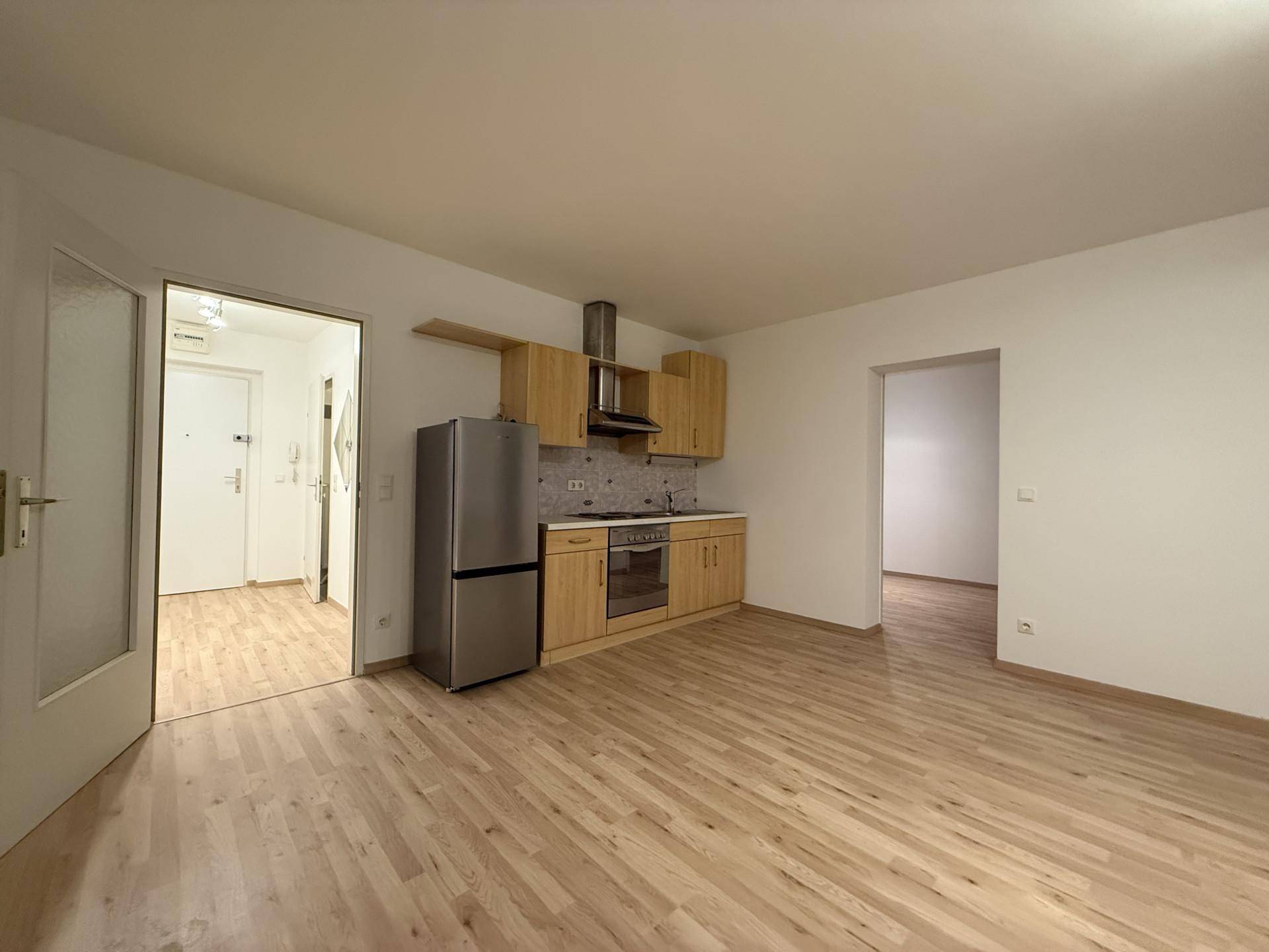 Offene Küchenzeile mit Holzschränken und Zugang zu angrenzenden Räumen, ausgestattet mit Laminatboden.