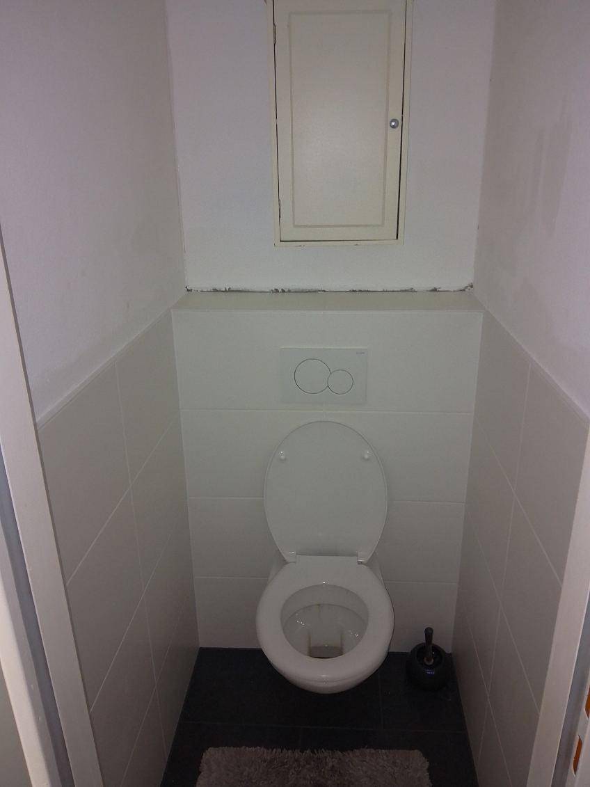 Separates WC mit wandhängender Toilette und weißen Fliesen, funktional und sauber.