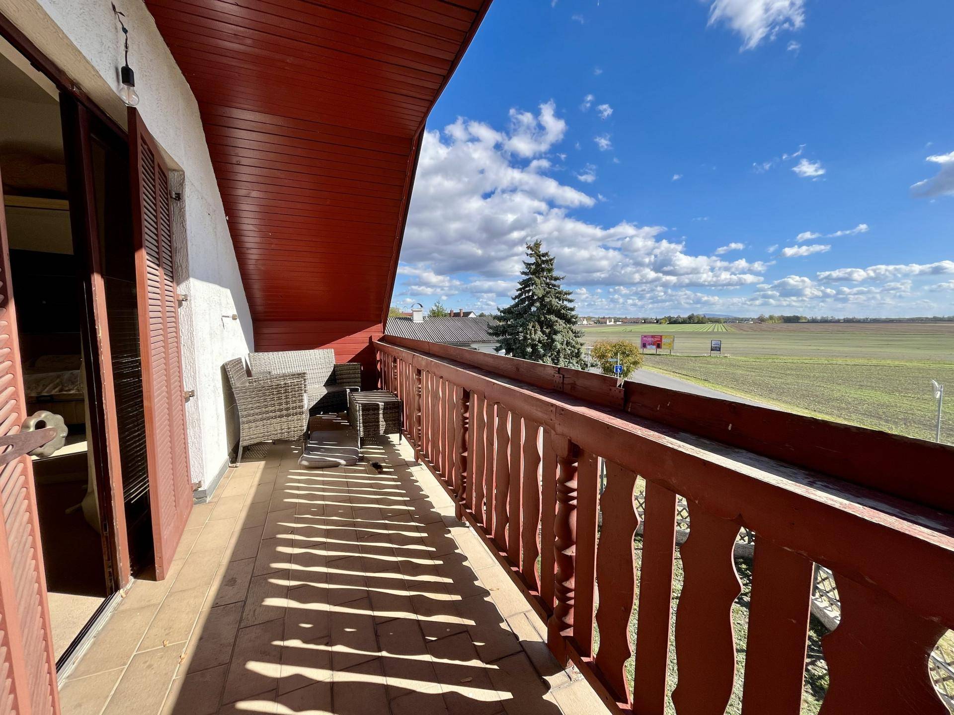 Geräumiger Balkon mit Holzboden und weitem Blick über die grüne Landschaft.