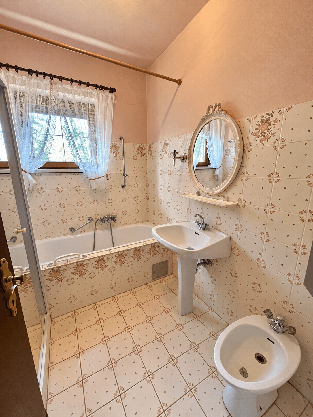 Badezimmer mit Badewanne, Waschbecken, Bidet und charmanten floralen Fliesen.