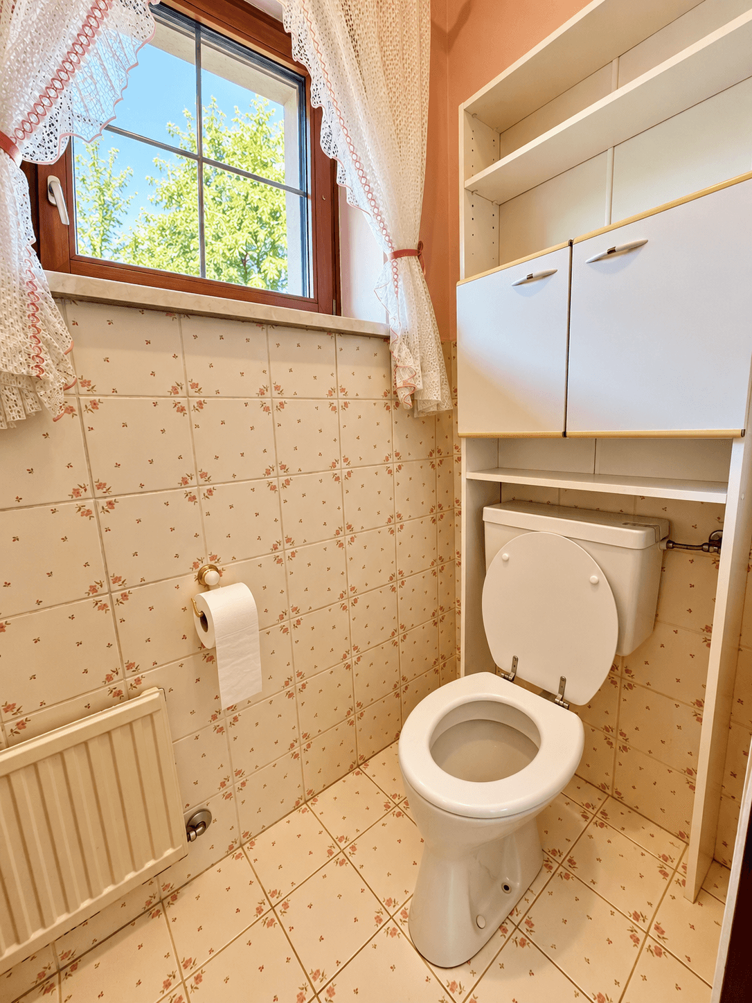 WC mit Toilette, Waschbecken und Fenster, ausgestattet mit charmanten Fliesen.