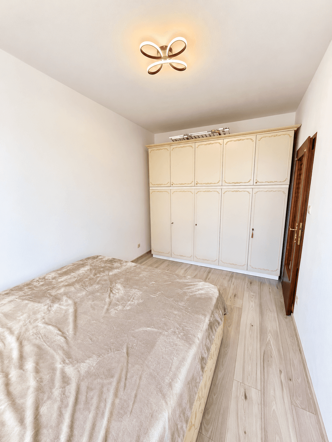Gemütliches Schlafzimmer mit Doppelbett, großem Kleiderschrank und hellem Laminatboden.