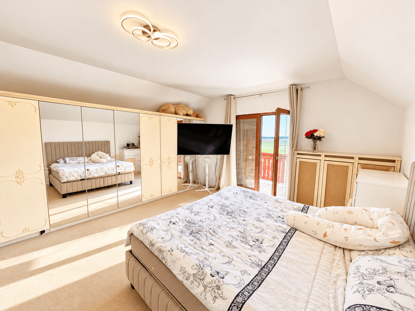 Helles Schlafzimmer mit Balkonzugang und weitem Blick über die umliegende Landschaft.