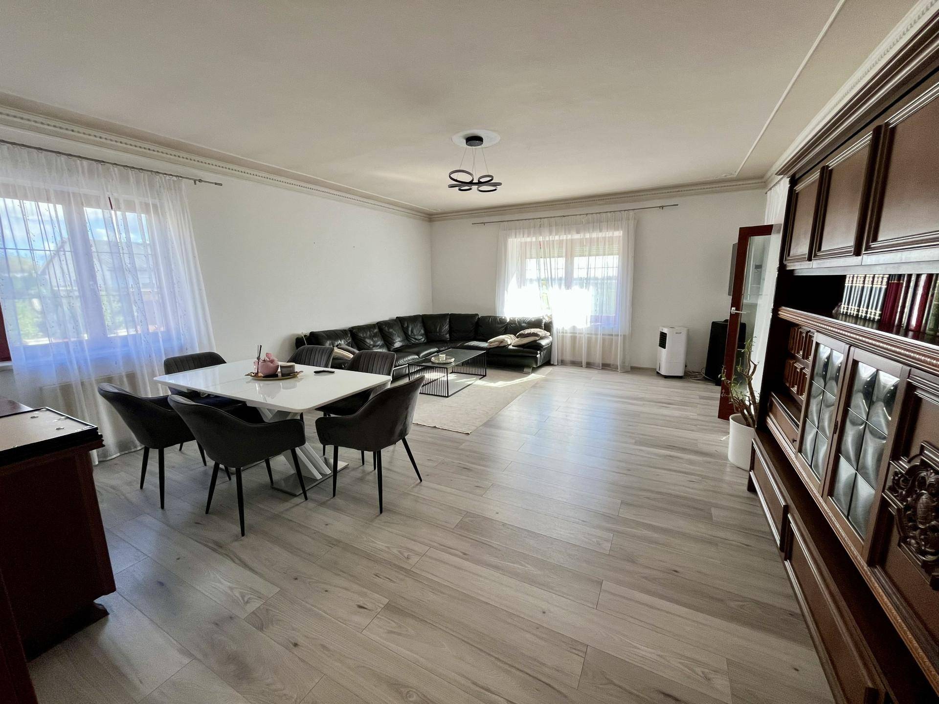 Geräumiger Wohn-Essbereich mit modernem Sofa, Esstisch und traditionellem Holzschrank.
