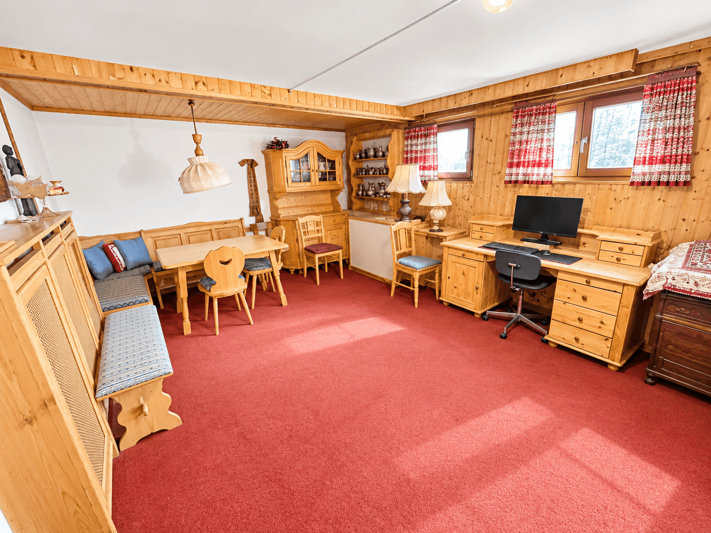 Gemütliches Wohnzimmer im alpinen Stil mit Holzvertäfelung, traditionellen Möbeln und rotem Teppich.