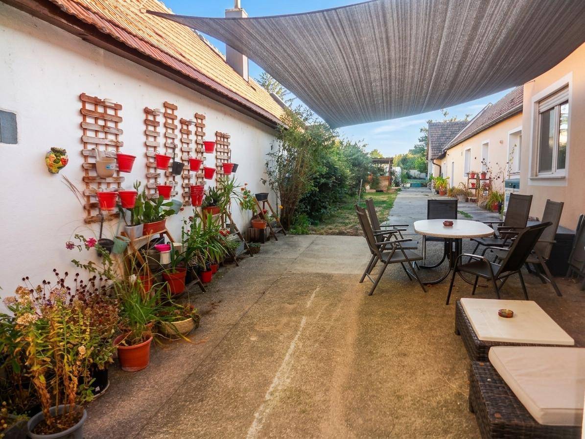 Gemütlicher Innenhof mit Sitzgelegenheiten, Pflanzen und einem Sonnensegel für Schatten.