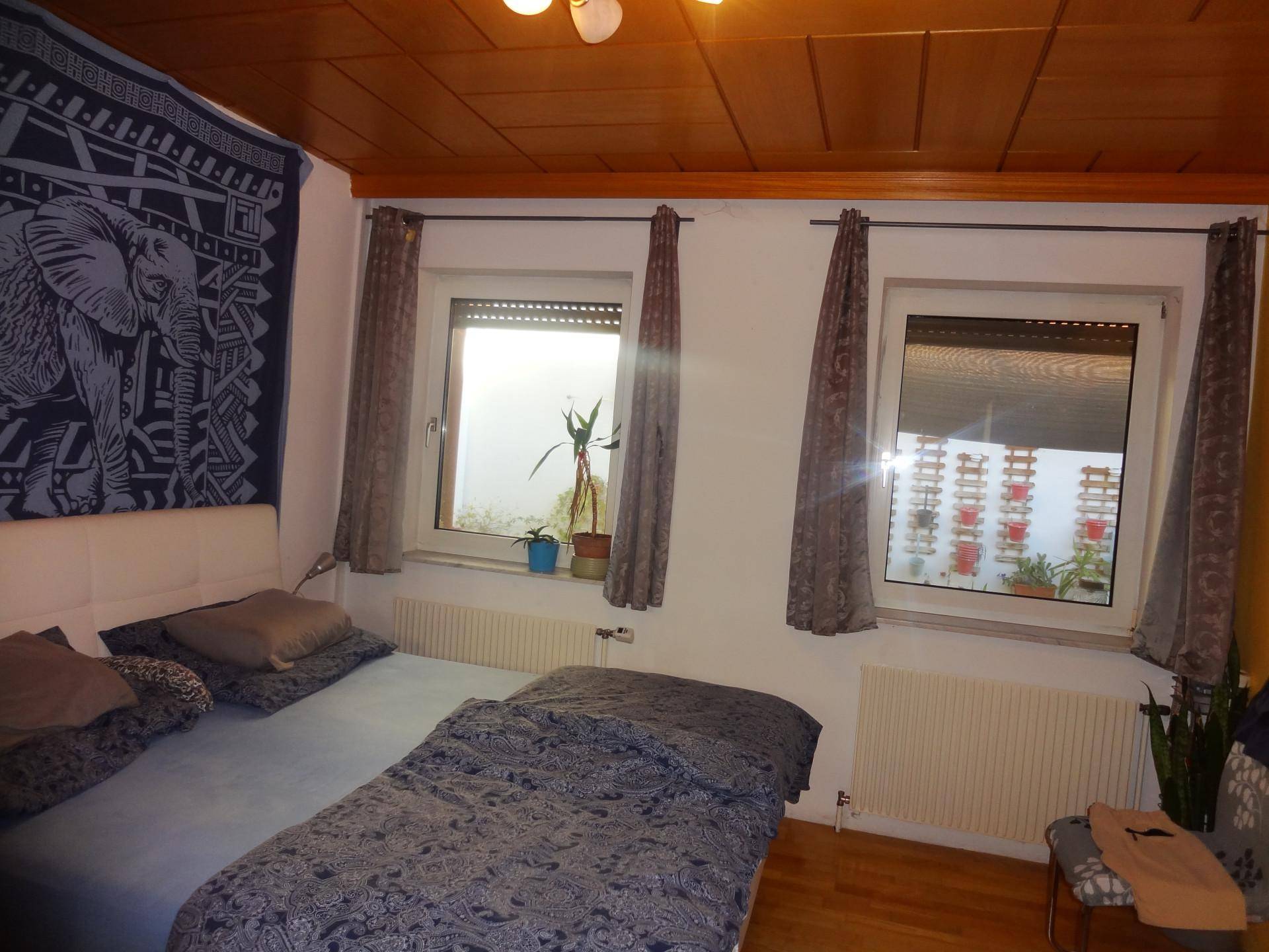 Schlafzimmer mit Holzbalkendecke, Doppelbett und Blick auf den Innenhof.