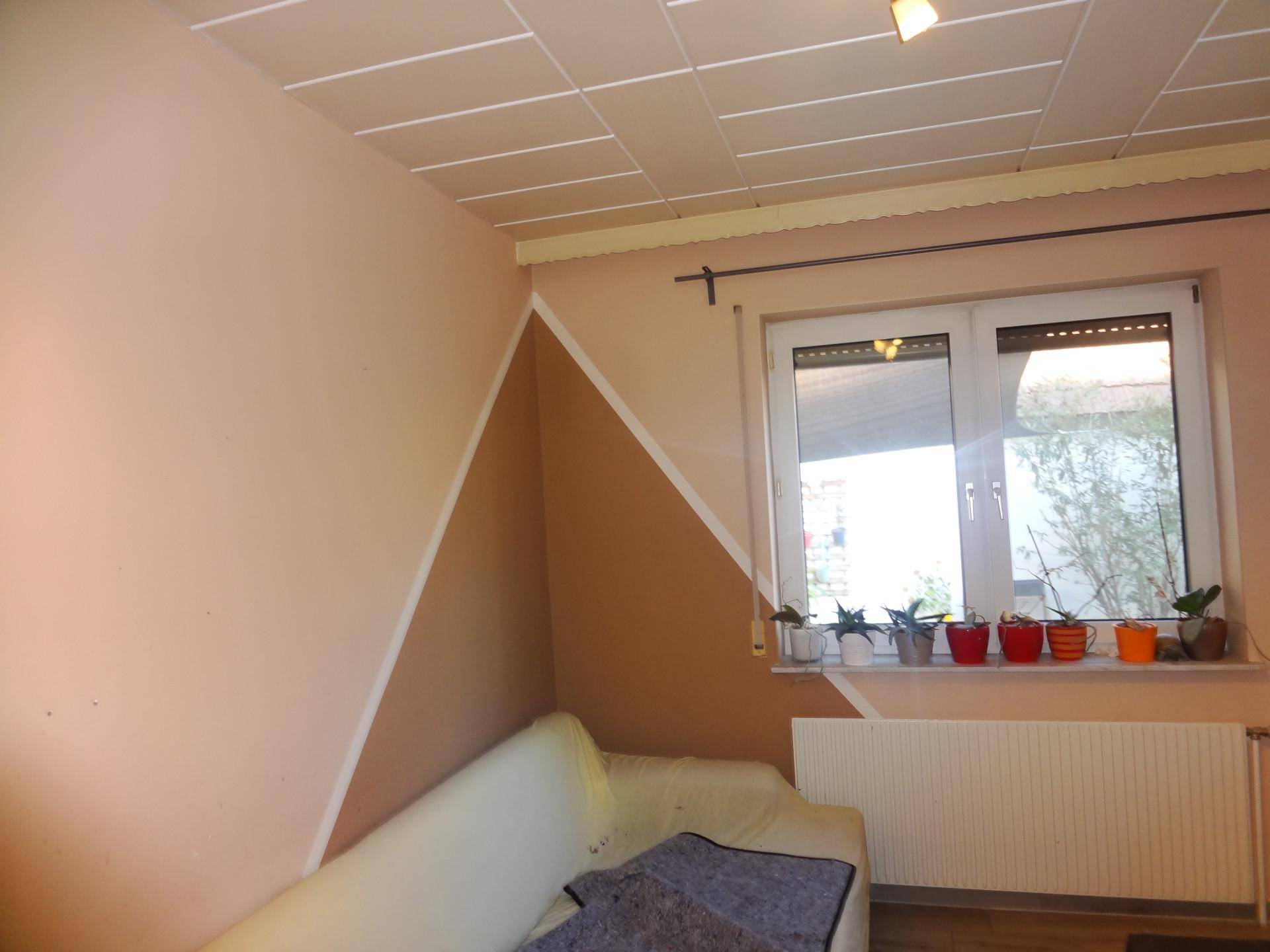 Heller Raum mit Fenster, Heizung und dekorativer Wandgestaltung in Pastelltönen.