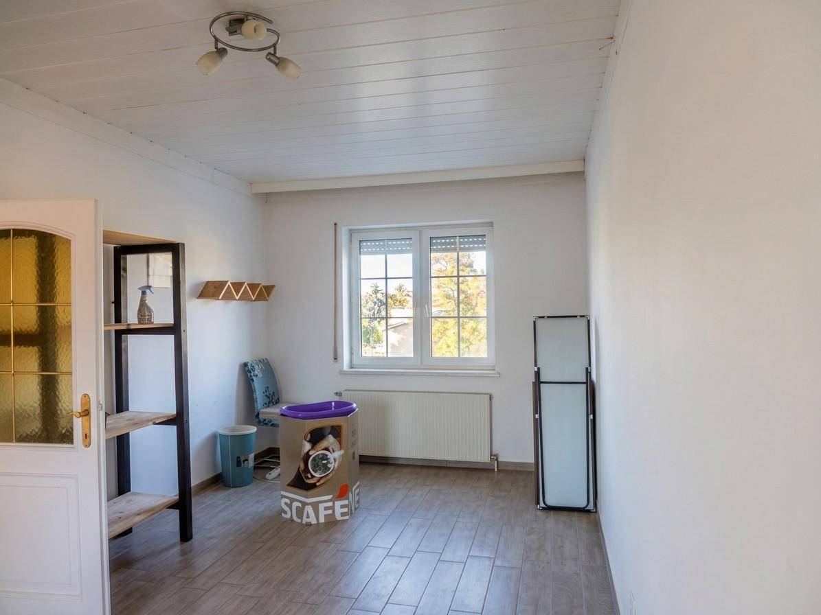 Heller Raum mit Fenster, Heizung und einfacher Einrichtung, vielseitig nutzbar.