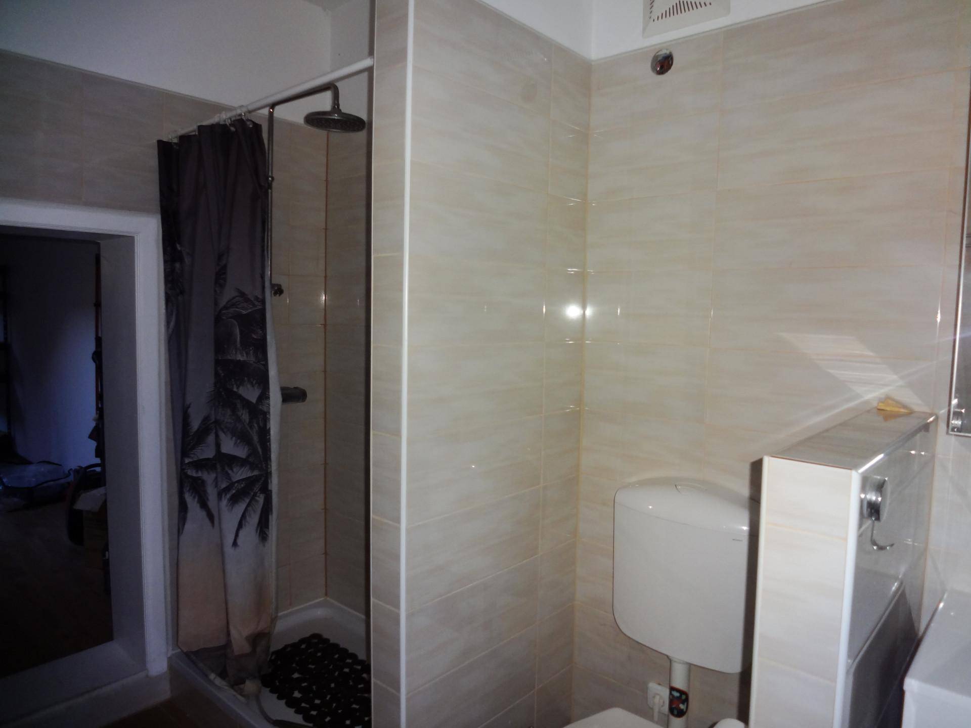 Badezimmer mit Duschkabine, WC und hellen Wandfliesen, funktional und sauber.
