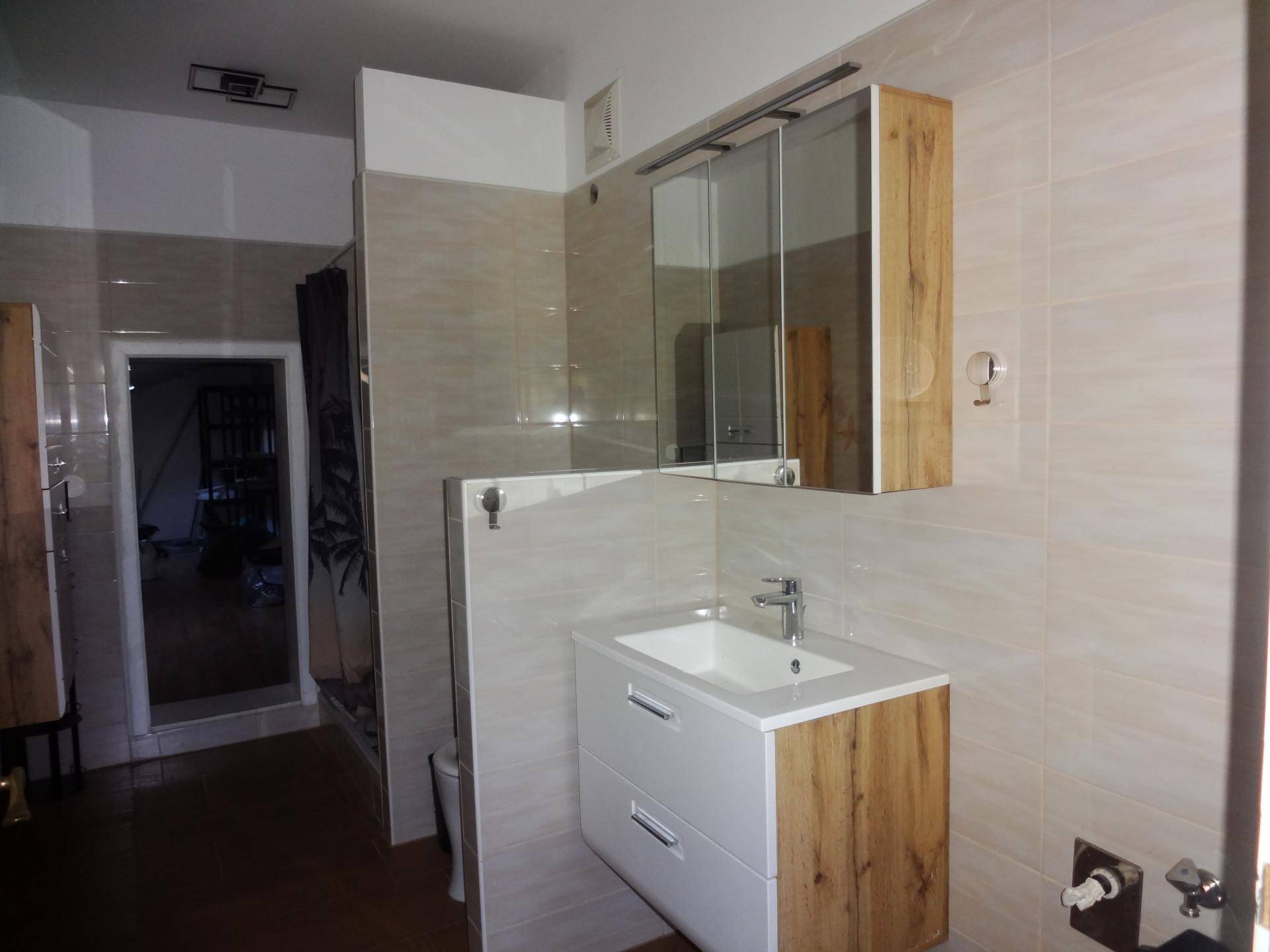 Modernes Badezimmer mit Waschbecken, Spiegelschrank und hellen Fliesen an den Wänden.
