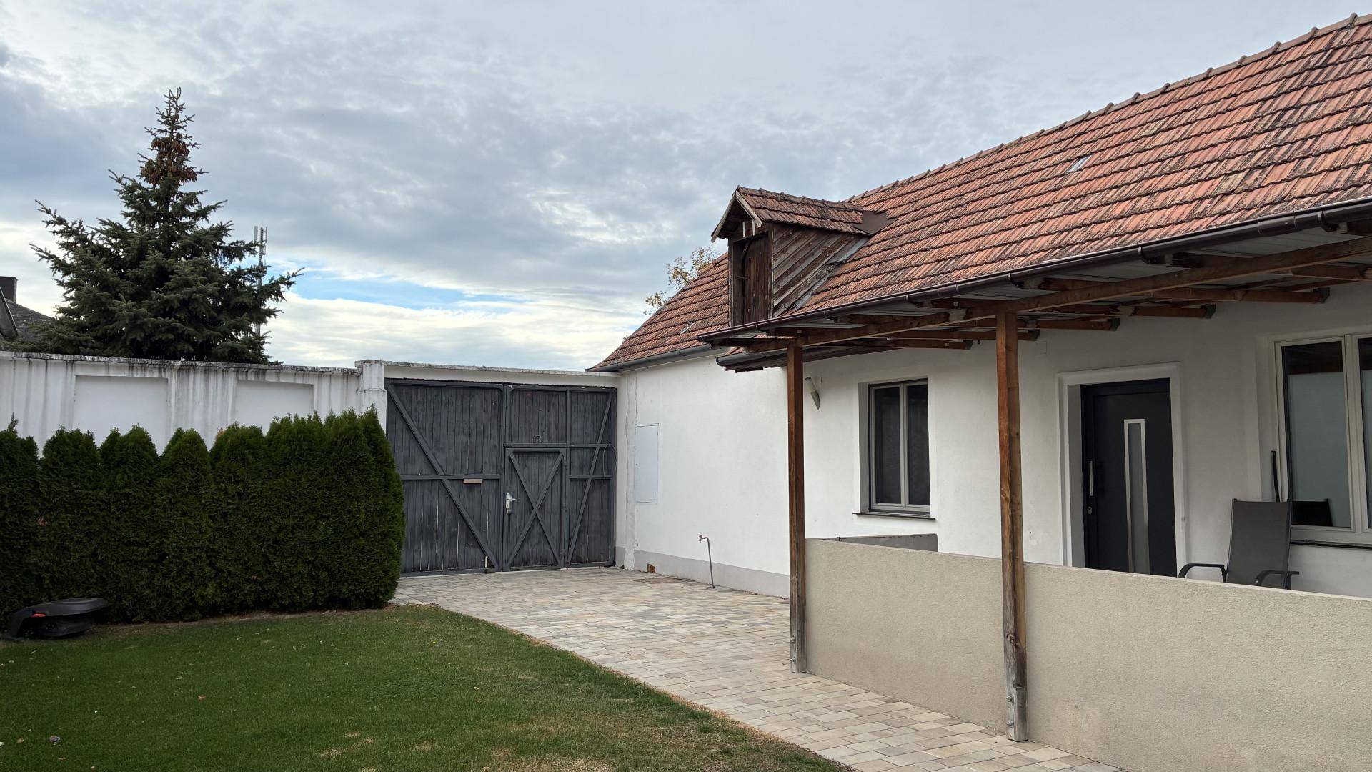 Seitenansicht des Hauses mit Garage, grüner Hecke und gepflegtem Rasenbereich.