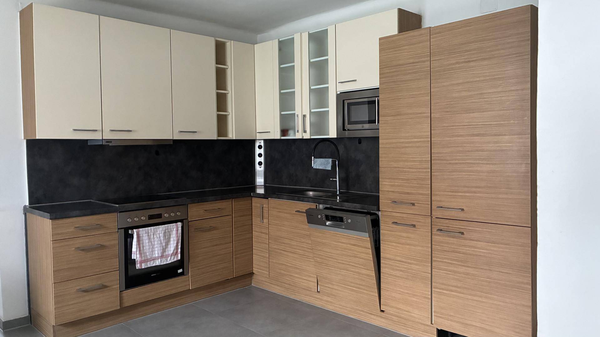 Moderne Einbauküche mit hellen und holzfarbenen Schränken sowie integrierten Geräten.