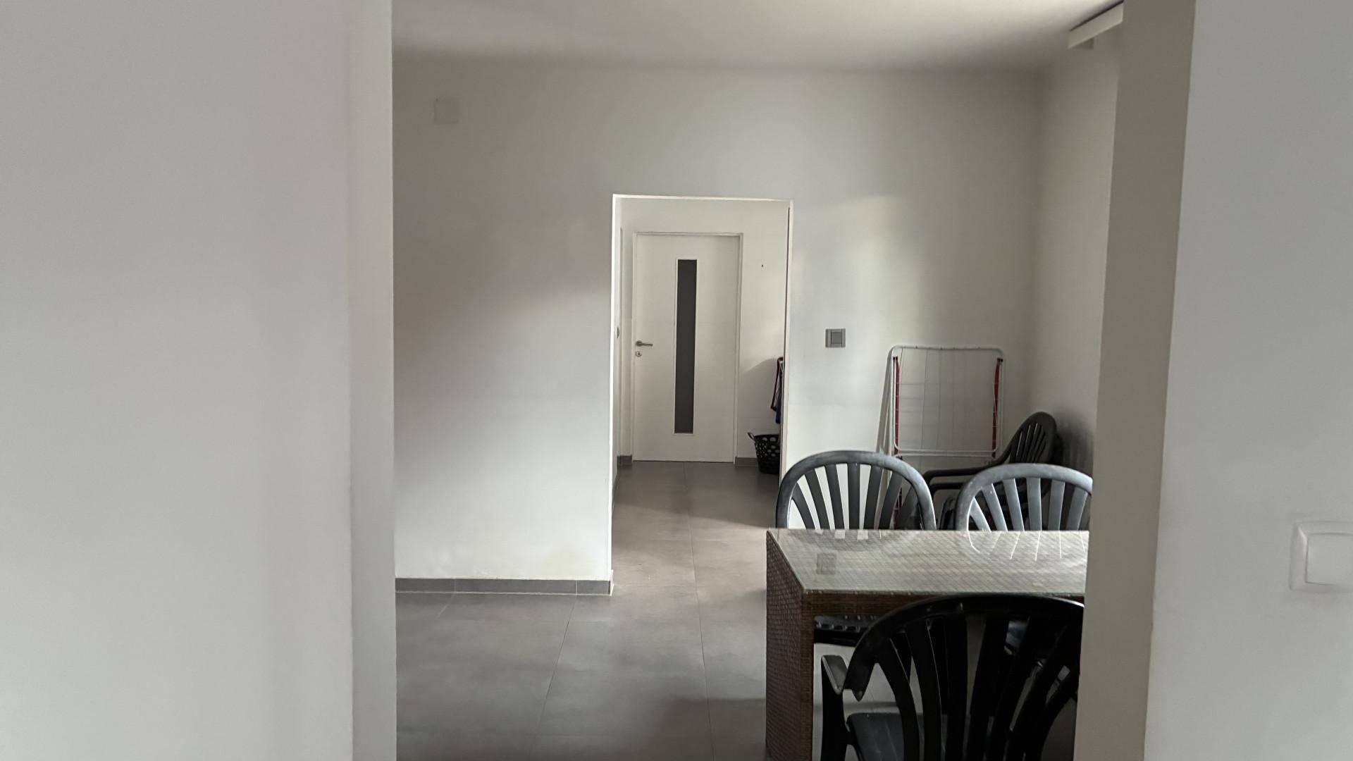 Essbereich mit einem Tisch und schwarzen Stühlen, angrenzend an einen Flur.