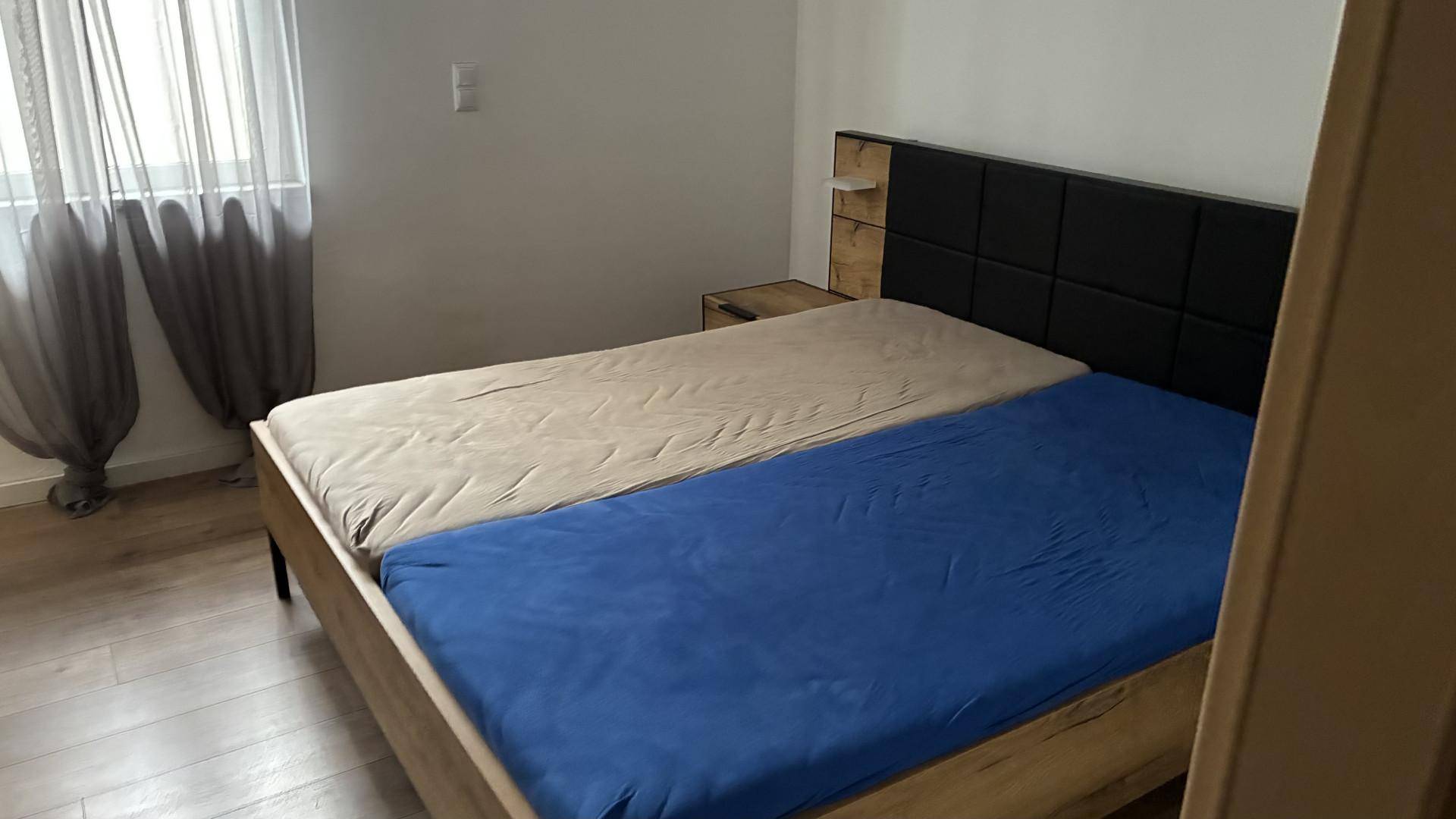 Schlafzimmer mit Holzbett, dunklem Kopfteil und hellem Holzboden.