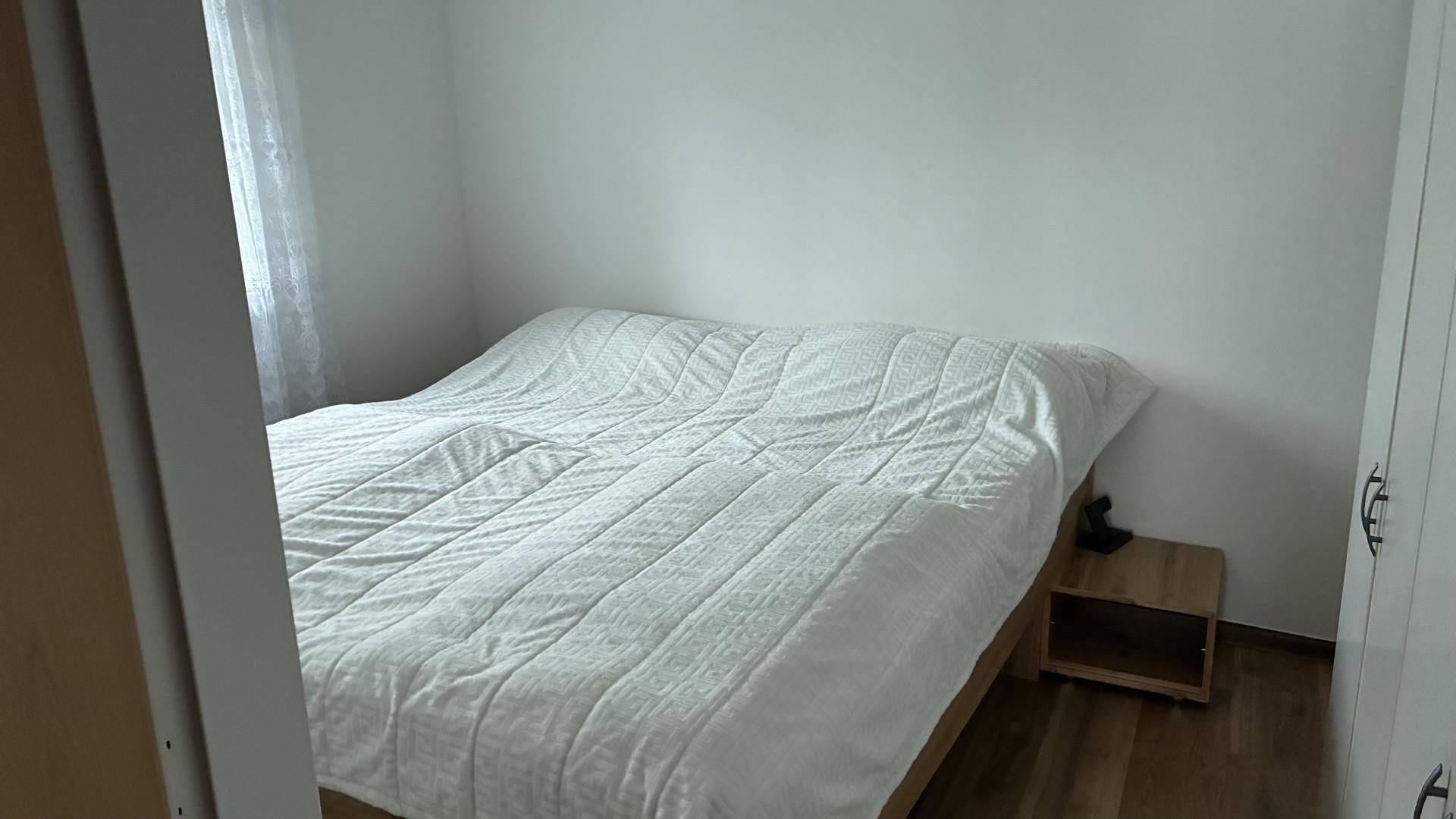 Schlafzimmer mit Doppelbett, weißer Bettwäsche und hellem Holzboden.