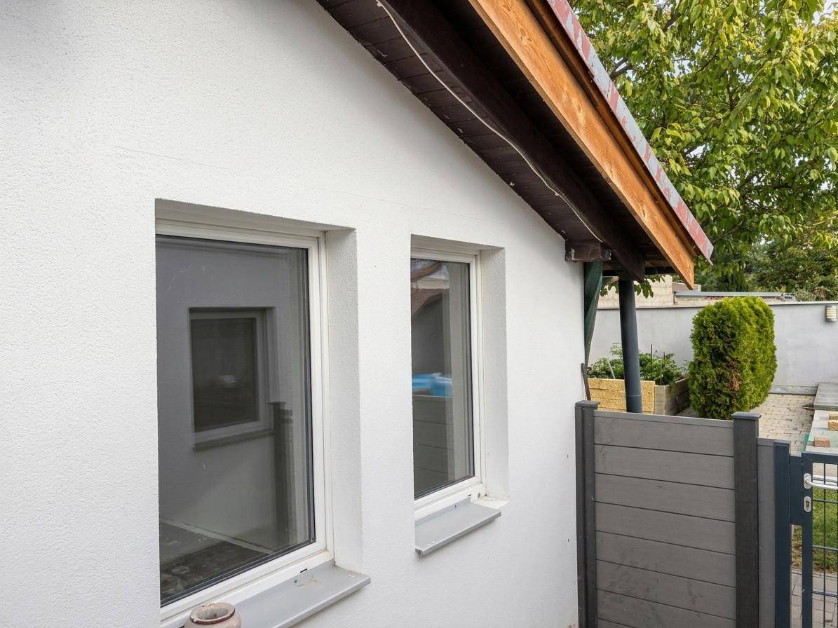 Nahaufnahme der weißen Fenster und der Fassade eines Gebäudes mit Holzdachüberstand.