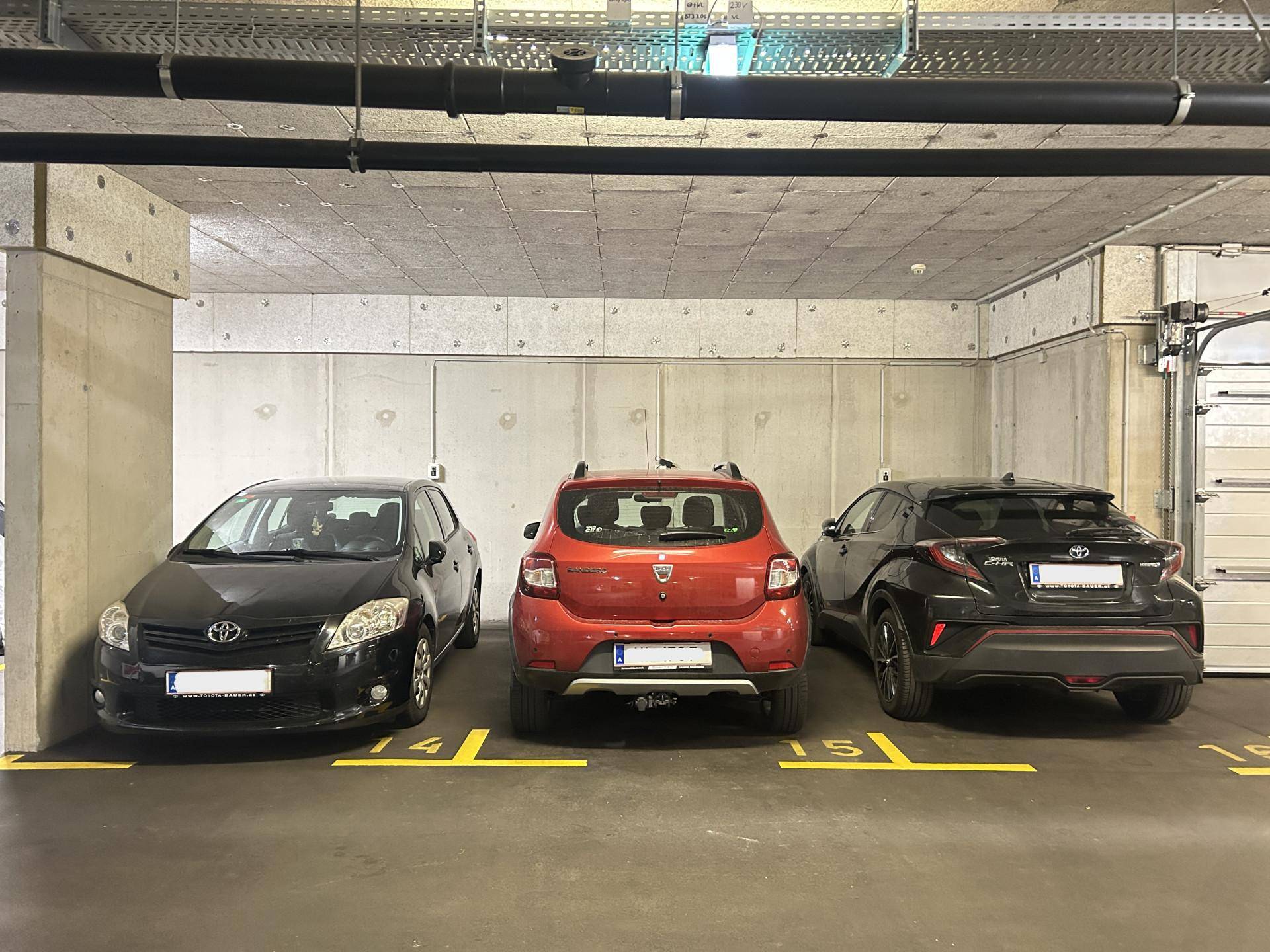 Geräumige Tiefgarage mit mehreren geparkten Fahrzeugen und nummerierten Stellplätzen.