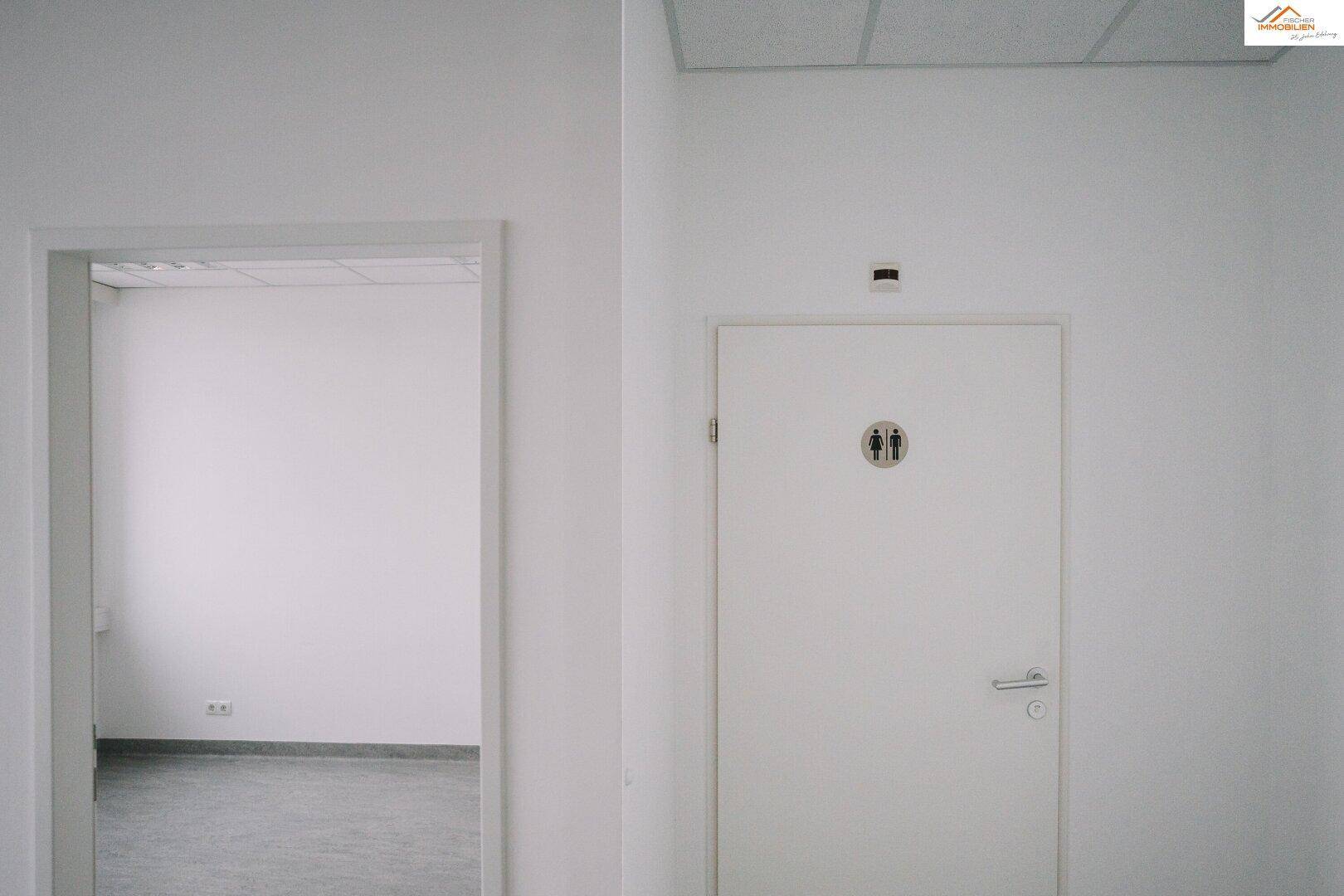 Heller Flur mit einer Tür zu einer Toilette und einem weiteren Raum.