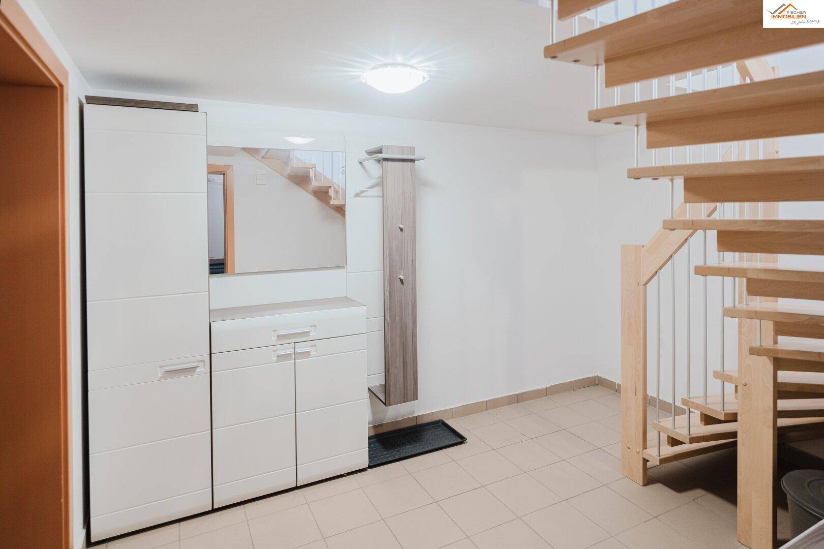 Eingangsbereich mit Holztreppe, Garderobe und praktischen Aufbewahrungsschränken.