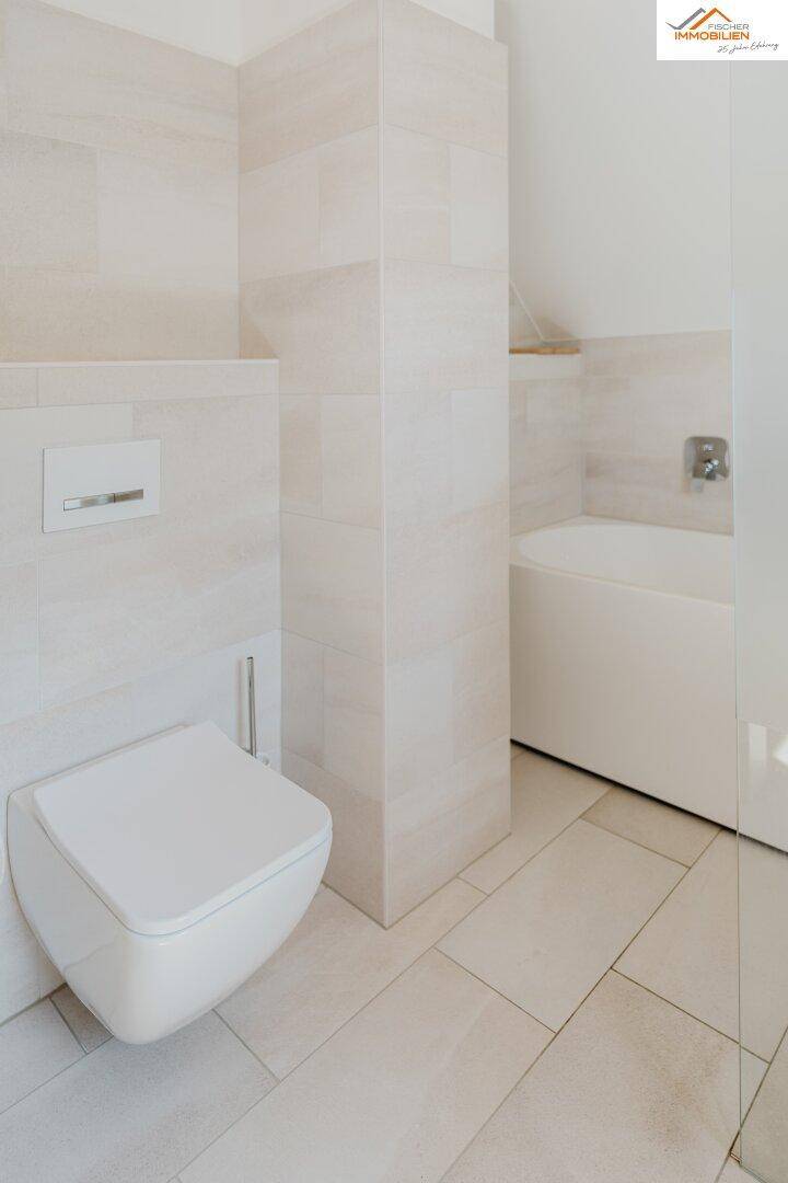 Helles Badezimmer mit wandhängendem WC und integrierter Badewanne.