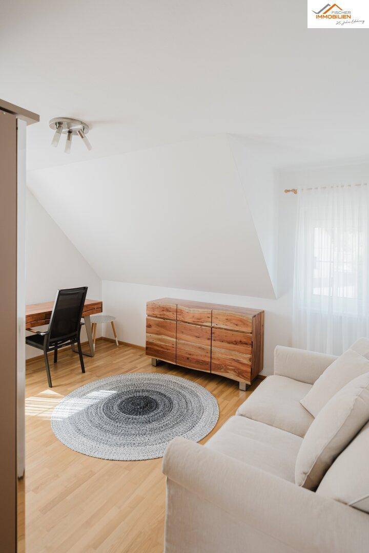 Gemütlicher Wohn- oder Schlafbereich mit Sofa, Holzkommode und Dachschräge.