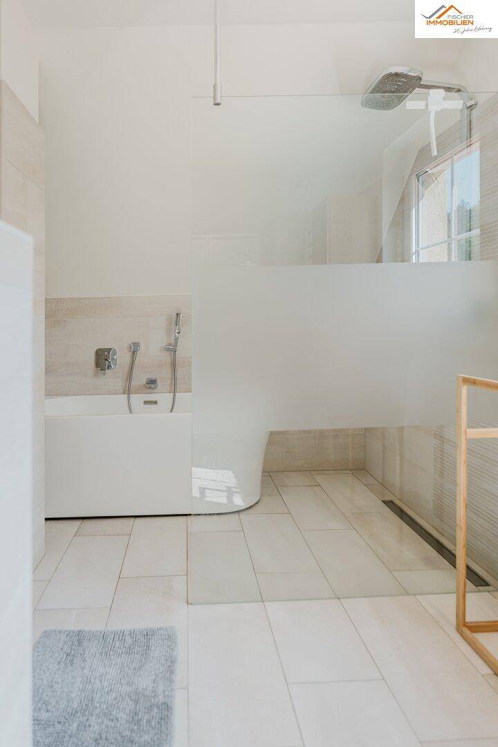 Geräumiges Badezimmer mit begehbarer Dusche und Badewanne, hell gefliest.