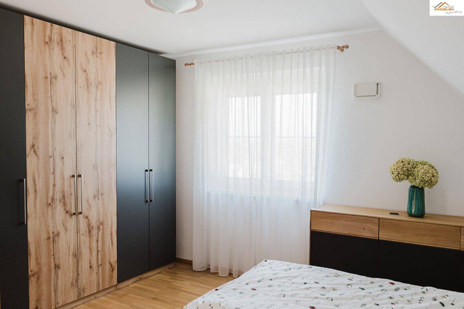 Geräumiges Schlafzimmer mit großem Kleiderschrank, Doppelbett und viel Tageslicht.