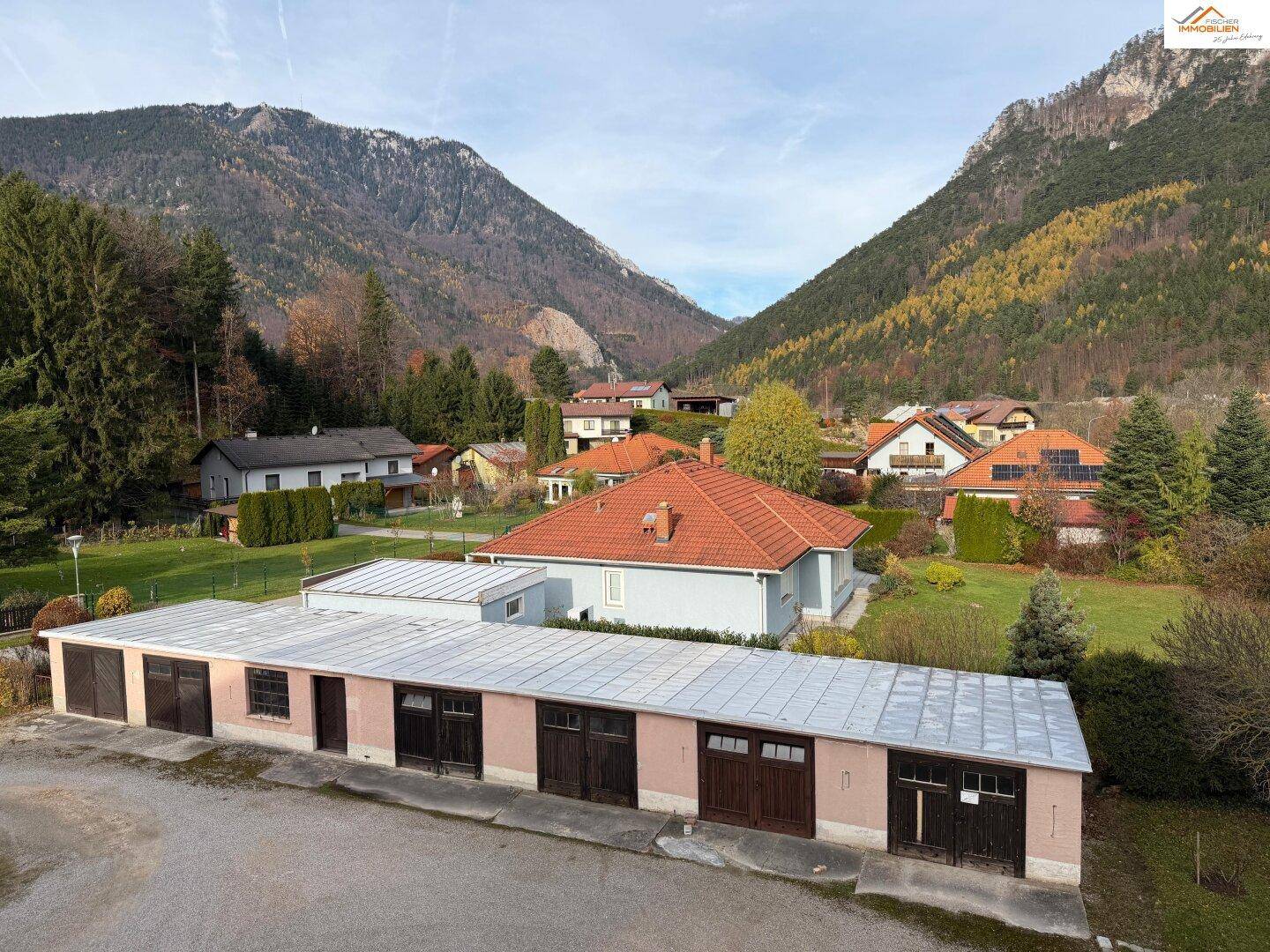 Panoramablick auf die Berglandschaft mit Wohnhäusern und einer Reihe von Garagen im Vordergrund.