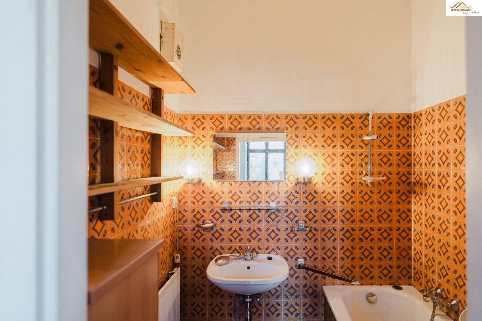 Badezimmer mit orangefarbenen Fliesen, Waschbecken und Badewanne, das eine Modernisierung benötigt.